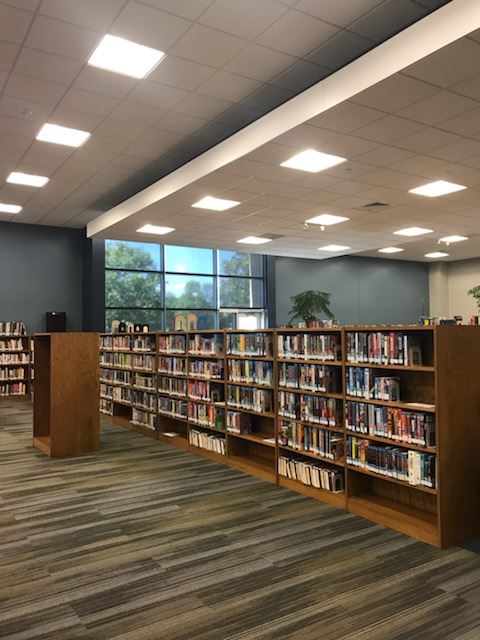 A library filled with numerous books and a few chairs for reading and studying